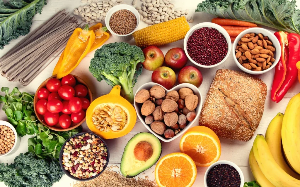 A imagem apresenta um grupo de alimentos ricos em fibras solúveis para emagrecer como laranjas, pimentão amarelo, grãos entre outros.