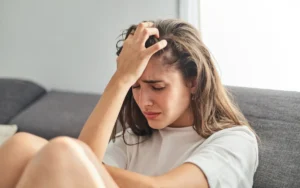 Mulher com a mão na cabeça em situação de desespero causado pelo transtorno de ansiedade generalizada (TAG).
