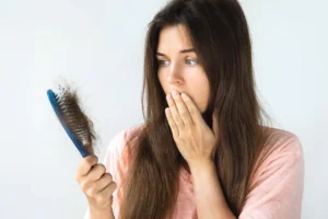 Mulher assustada ao perceber queda de cabelo.