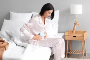 Mulher com bolsa térmica para aliviar a cólica menstrual.