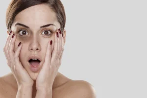Mulher espantada ao ver manchas de olheiras ao redor dos olhos.
