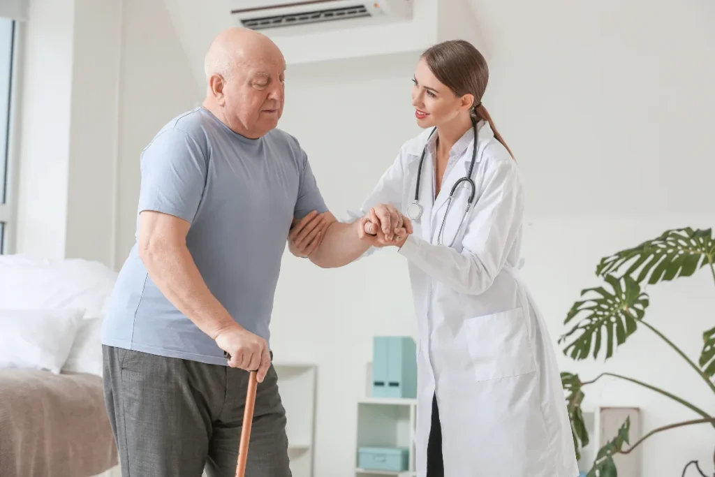 Médica auxiliando paciente idoso que sofre de Doença de Parkinson.