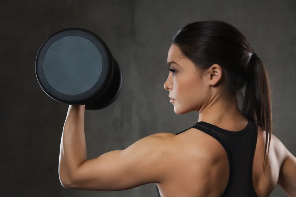 Mulher flexionando os músculos para ganhar massa muscular.