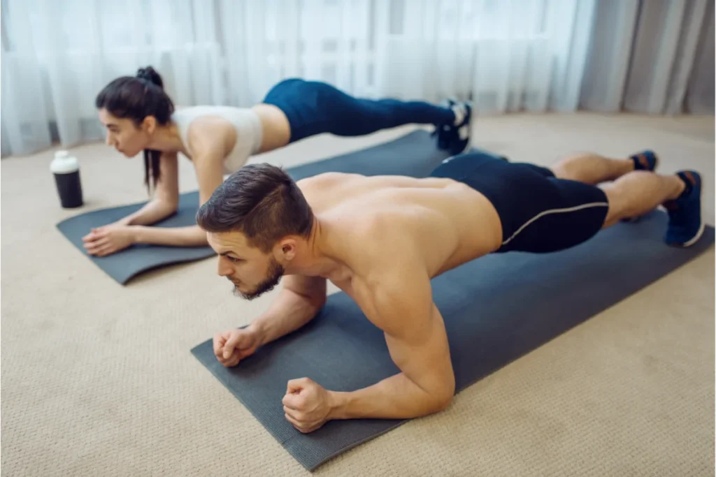 Casal realizando treino em casa para tonificar o corpo.