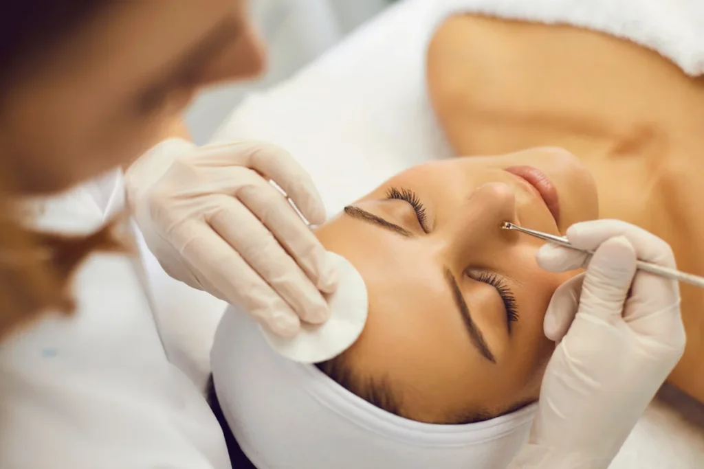 Esteticista realizando limpeza de pele na mulher.