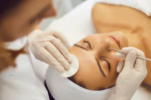 Esteticista realizando limpeza de pele na mulher.