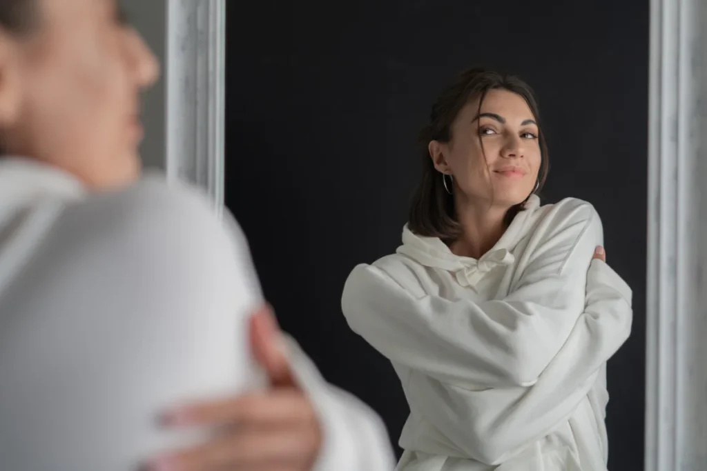 Mulher jovem contemplando sua imagem no espelho.