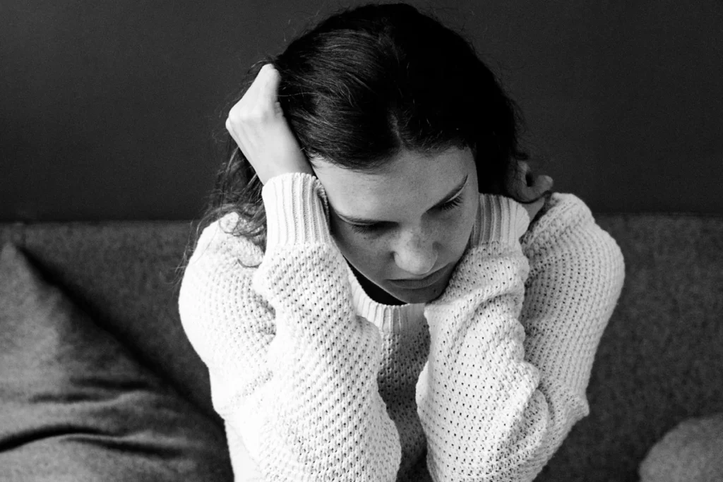 Mulher jovem demonstrando sinais típicos de depressão, como expressão de tristeza e isolamento.