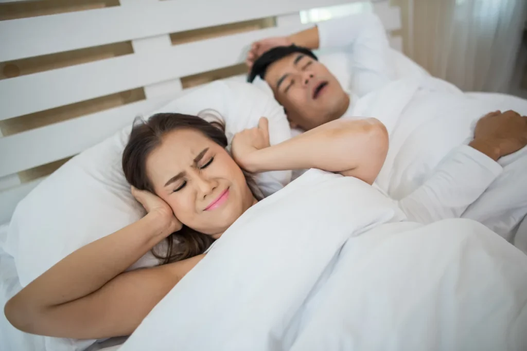Homem com apneia do sono causa desconforto na esposa que bloqueia as orelhas.
