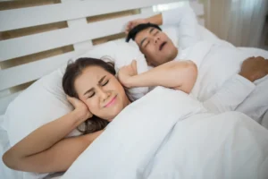 Homem com apneia do sono causa desconforto na esposa que bloqueia as orelhas.